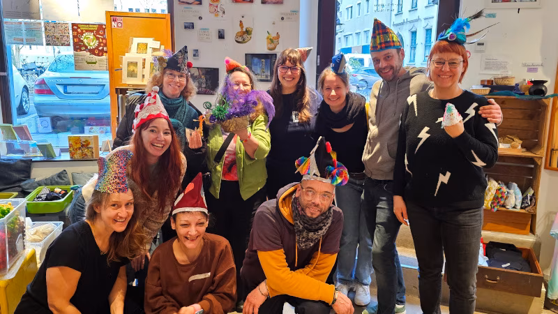 Eine Gruppe Leute, die gerade Nattenkappen gebastelt hat und die Ergebnisse fröhlich präsentiert