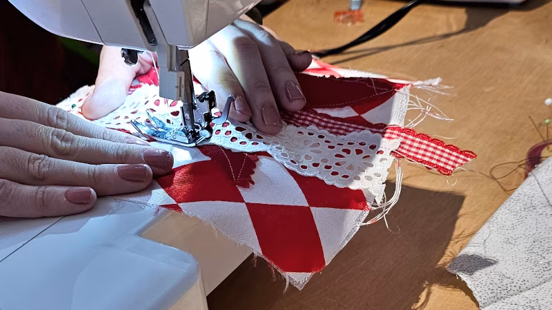Narrenkappenworkshop_IGLU_Nähen_260201_450x800 Weiße Spitze wird mit der Nähmaschine auf rot-weißen Stoff genäht