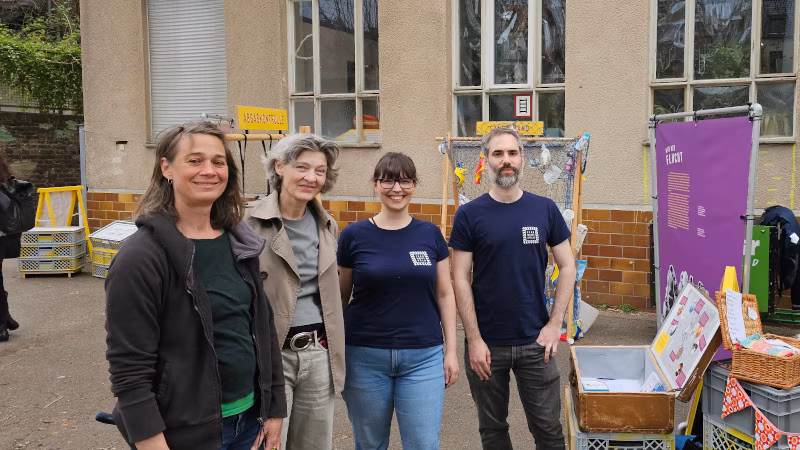 Das Team von Zero Waste Köln steht vor dem Zero Waste Parcours und lächelt in die Kamera. Im Hintergrund das Allerweltshaus.