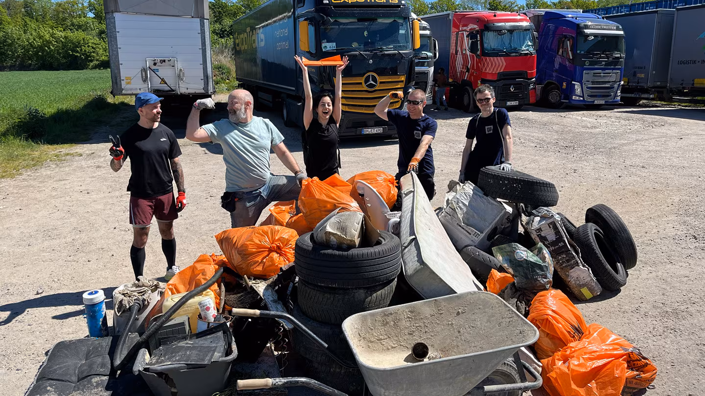 Fünf Ehrenamtliche stehen vor einem großen Haufen eingesammeltem Müll. Zu sehen sind Autoreifen, eine Matratze und orange Müllsäcke.