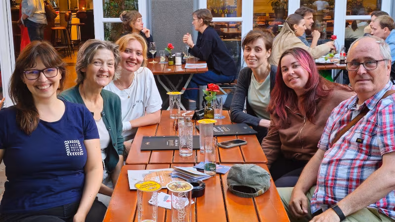 Das Team Schule lacht beim Stammtisch im Biergarten in die Kamera