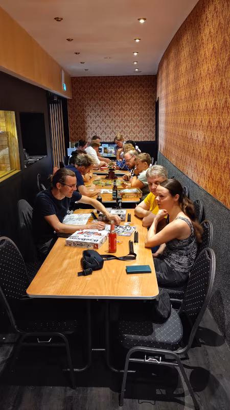 Spieletag im GLORIA Sommercafé Eine Gruppe Leute spielt im GLORIA Sommercafé, die Tische sind auf dem Gang aufgebaut