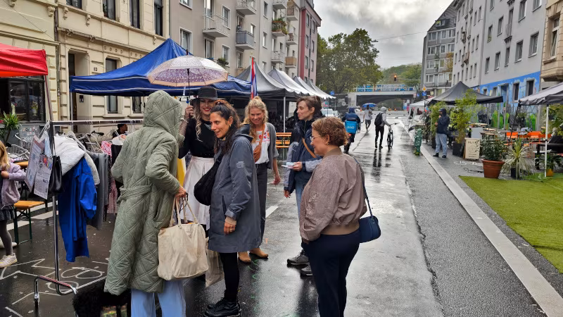 Laufaktion auf dem Tag des guten Lebens 2026 Leute unterhalten sich im leichten Regen über die mobile Tauschaktion, es sind viele Regenschirme und Pfützen zu sehen