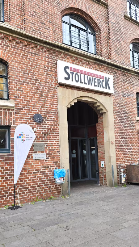 BNE-Festival 2026 Eingang des Bürgerhaus Stollwerk, daneben eine Beach Flag mit dem Logo des BNE-Festivals