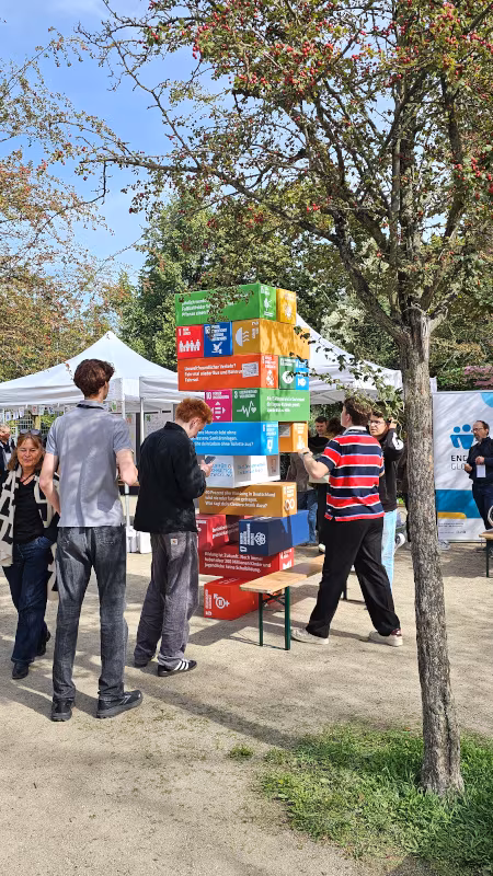 BNE-Festival 2026 Eine Gruppe junger Leute baut einen riesigen Jengaturm, darauf abgebildet die 17 SDGs